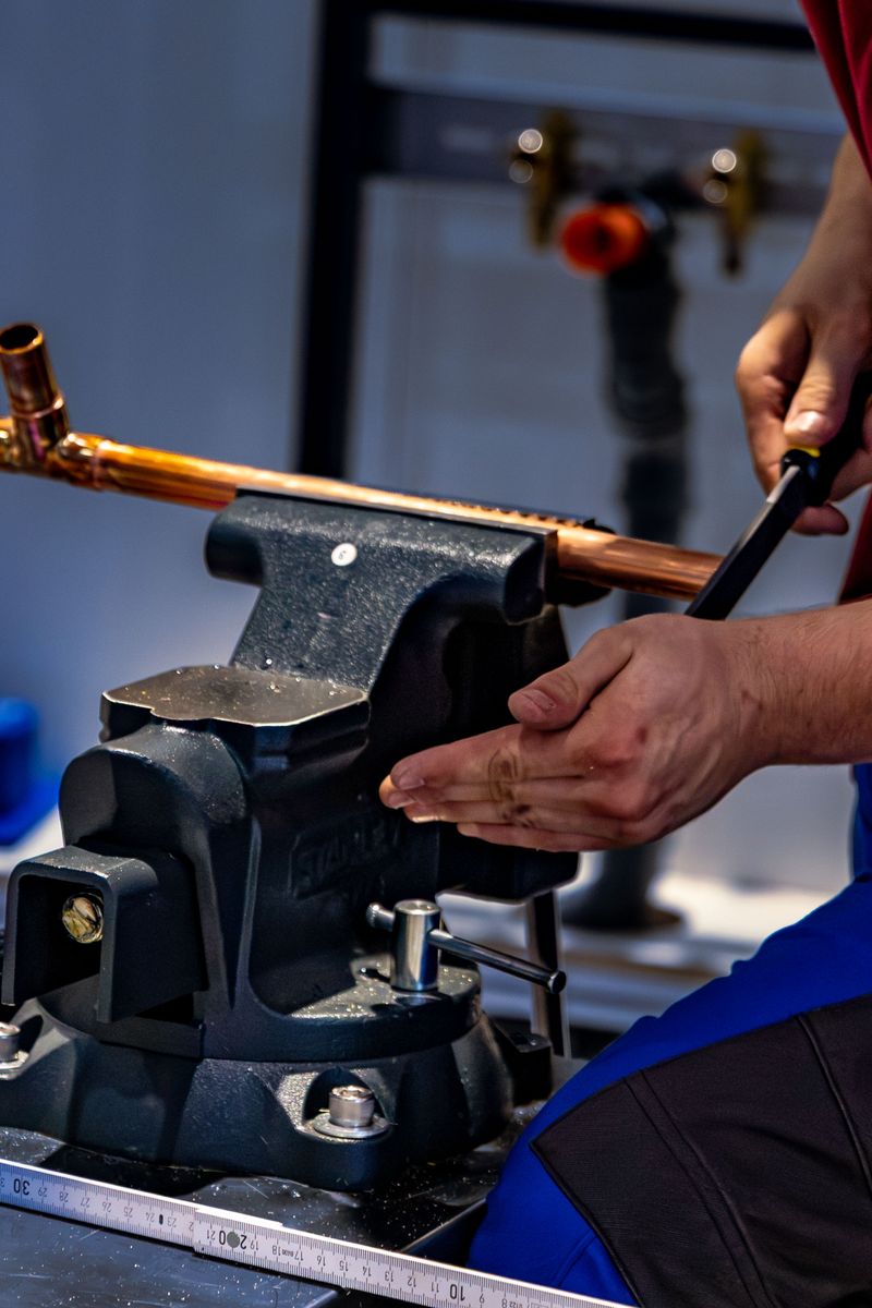 Close-up of hands bending copper pipe with a pipe bender